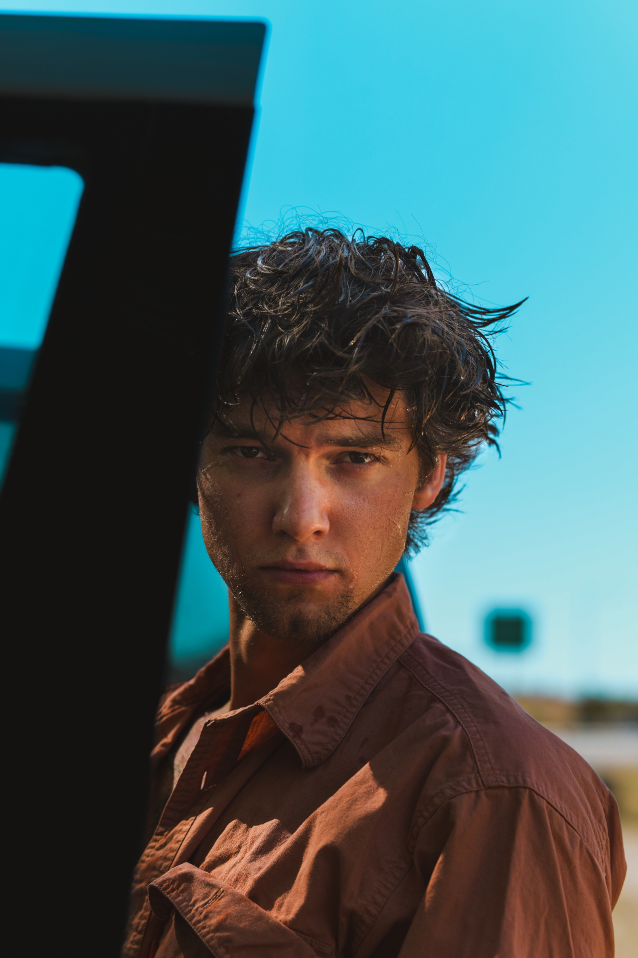Nick Bauer beside an open vehicle door under a clear blue sky, looking into the camera